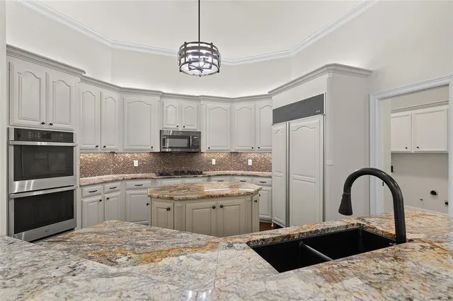 a kitchen with stainless steel appliances kitchen island a refrigerator sink and cabinets
