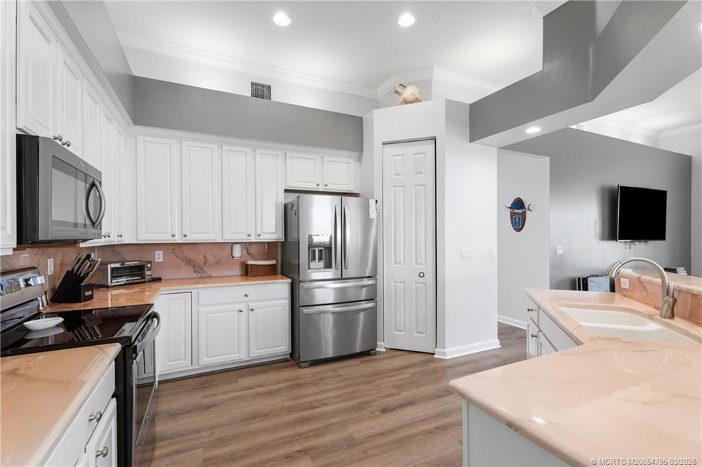 758 Southwest Blue Stem Way Stuart, FL 34997 - Photo 12 of 49 a kitchen with stainless steel appliances a sink stove refrigerator and cabinets