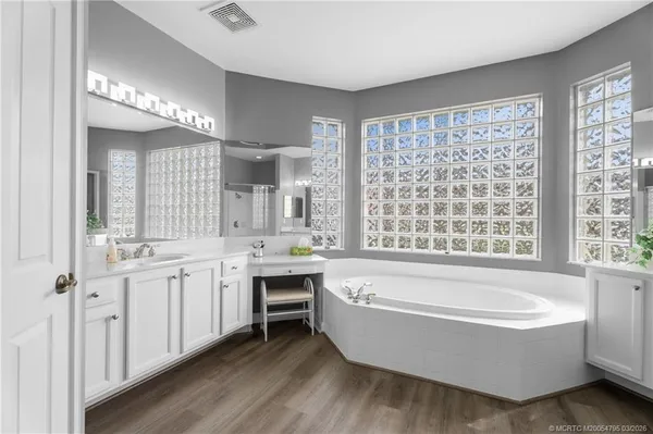 a bathroom with a tub a sink and a large window