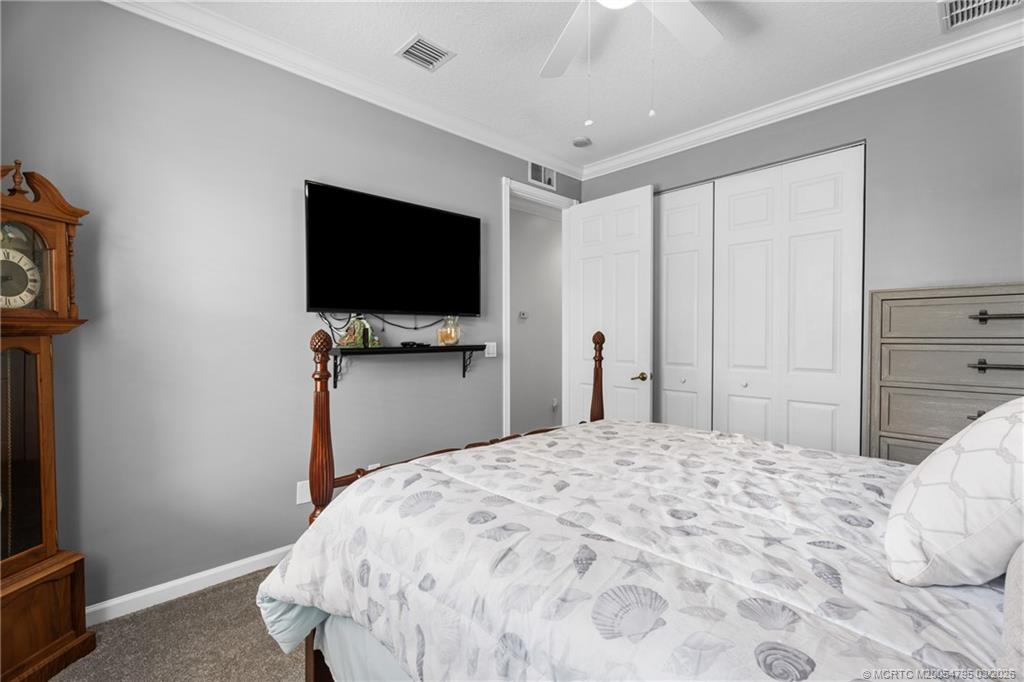 758 Southwest Blue Stem Way Stuart, FL 34997 - Photo 28 of 49 a bedroom with a bed and a flat tv screen on wall