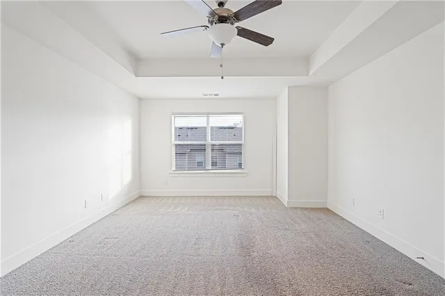 an empty room with a ceiling fan and windows