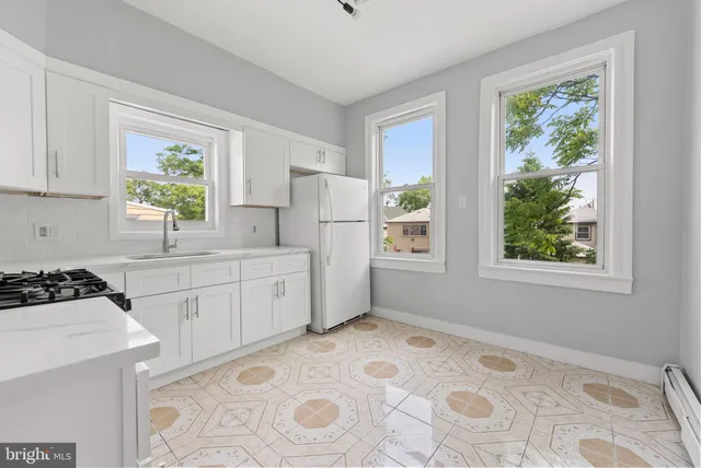 a kitchen with a stove a refrigerator sink and cabinets