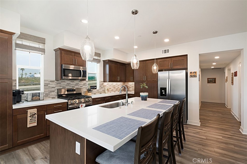 a kitchen with stainless steel appliances a sink a stove a refrigerator a dining table and chairs