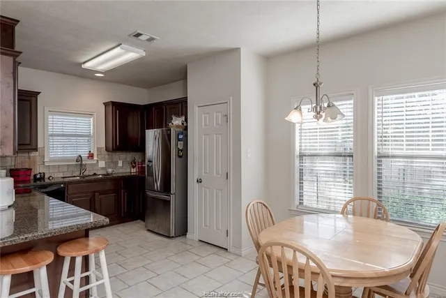 a kitchen with refrigerator a center island a dining table and chairs