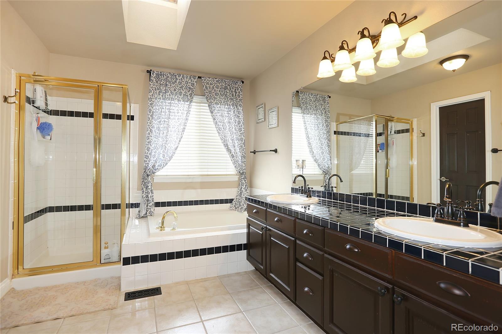 9764 Spring Hill Street Highlands Ranch, CO 80129 - Photo 19 of 32 a spacious bathroom with a double vanity sink a mirror and a bathtub