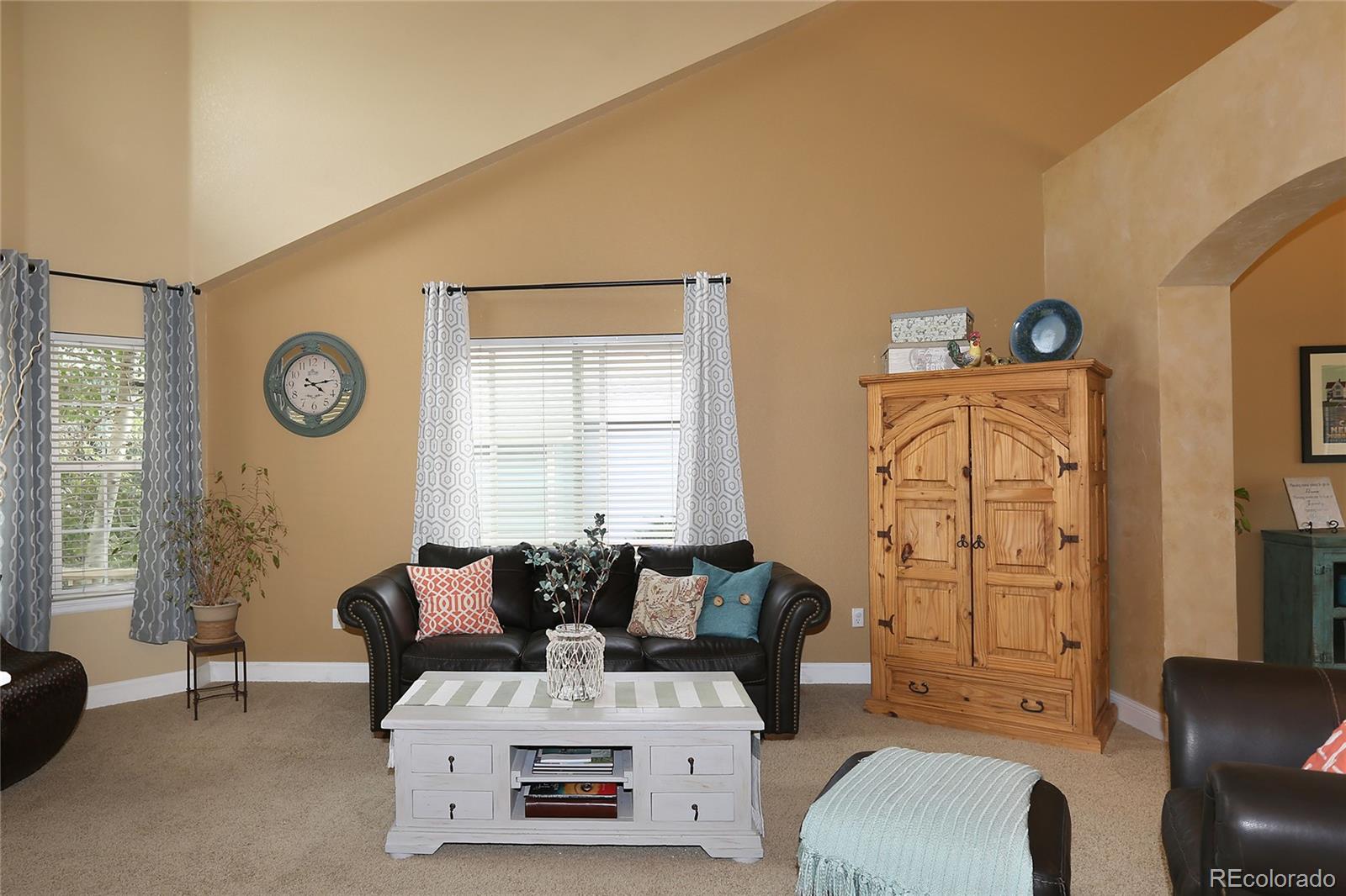 9764 Spring Hill Street Highlands Ranch, CO 80129 - Photo 4 of 32 a living room with furniture a clock on wall and a window