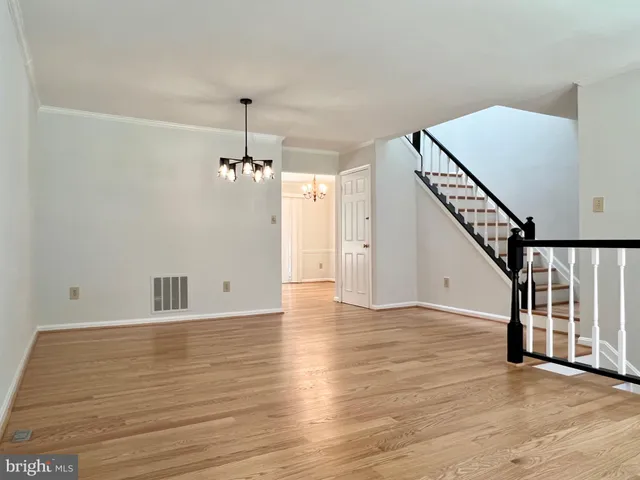 a view of an empty room with wooden floor windows and a chandelier