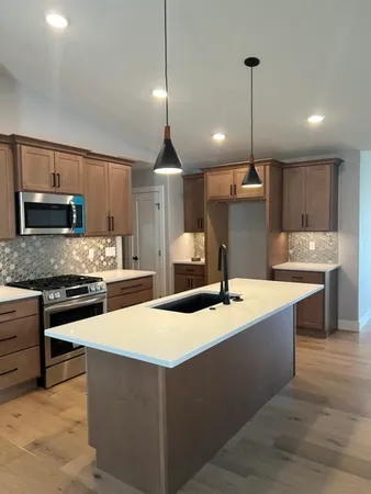 a kitchen with stainless steel appliances kitchen island granite countertop a sink a stove and a wooden floors