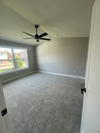 an empty room with windows and ceiling fan