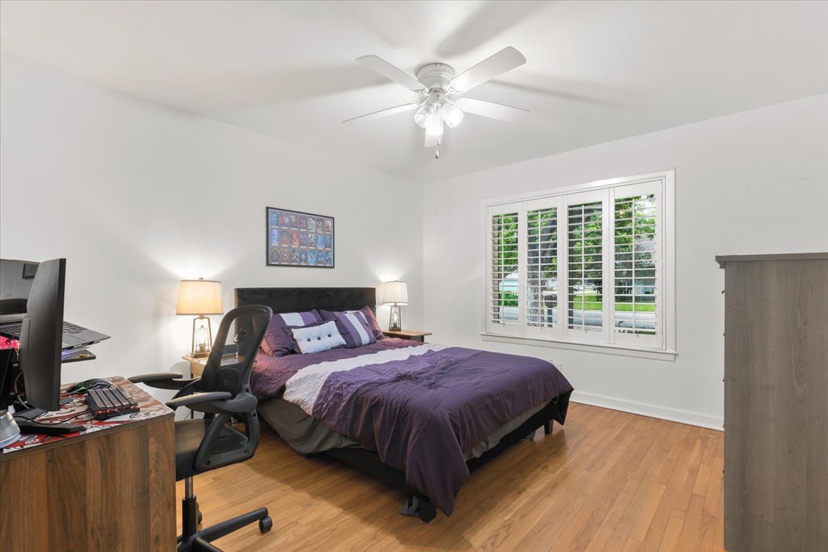 607 Short Street Smithville, TX 78957 - Photo 21 of 31 Bedroom with wood-finish flooring, a ceiling fan, and window featuring white plantation shutters