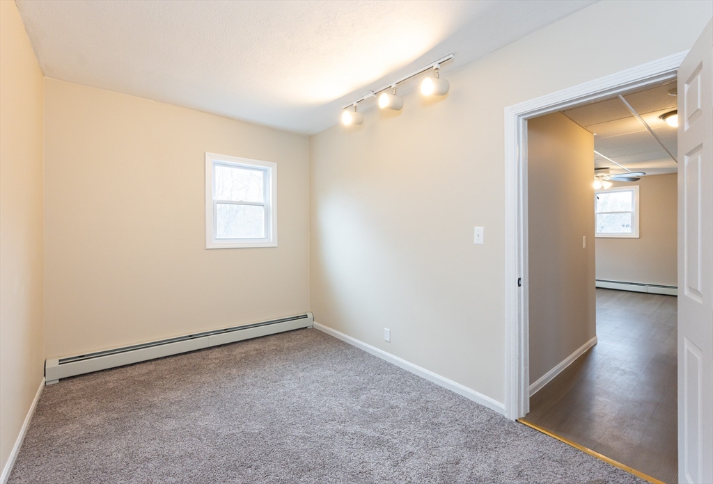29 Mill Street, Unit B Dracut, MA 01826 - Photo 22 of 37 an empty room with windows and wooden floor