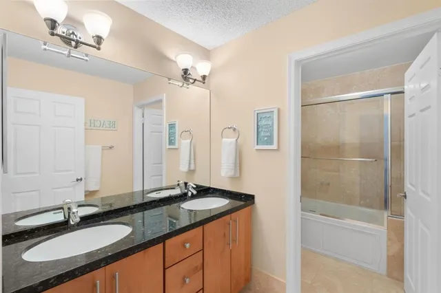 a bathroom with a granite countertop sink mirror and a shower