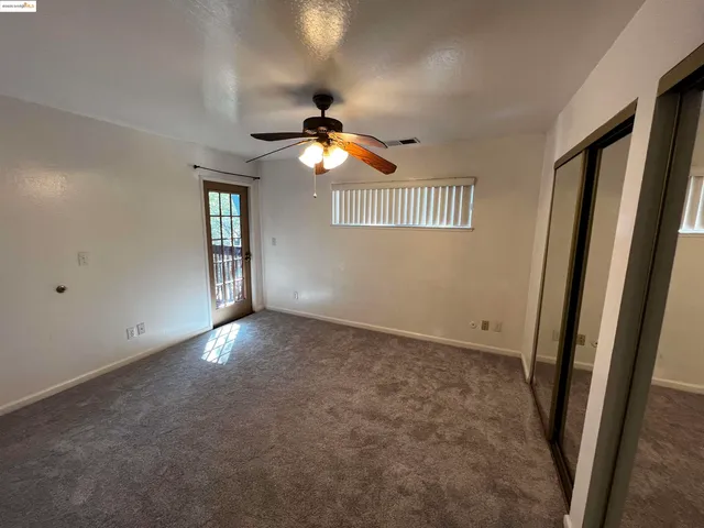 an empty room with windows and fan