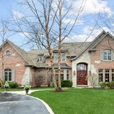 a front view of a house with a garden and trees