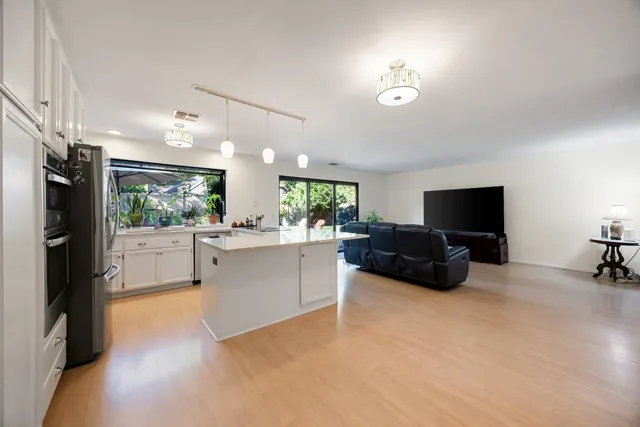 a living room with furniture a flat screen tv and a refrigerator