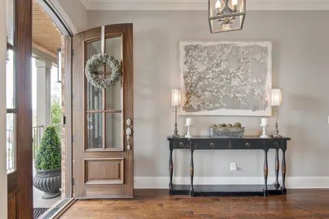 a dining room with wooden floor a chandelier a wooden table and chairs