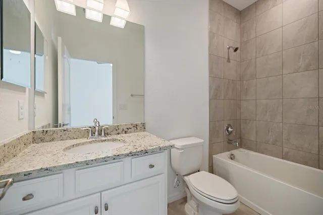 a bathroom with a granite countertop toilet a sink and bathtub