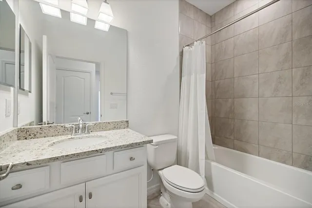 a bathroom with a granite countertop sink a toilet and bathtub