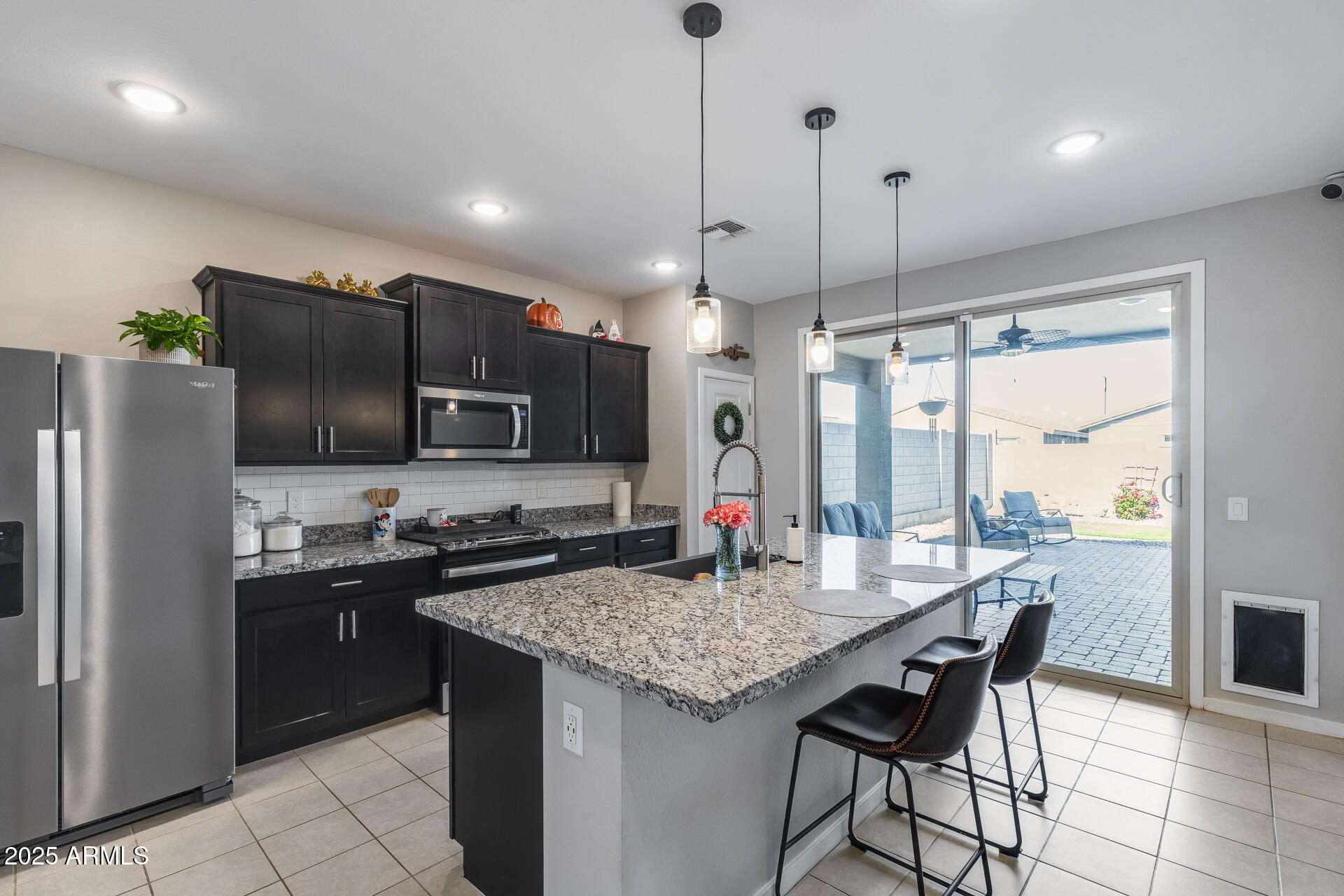 19920 West Rancho Drive Litchfield Park, AZ 85340 - Photo 3 of 49 a kitchen with granite countertop a table chairs microwave and refrigerator