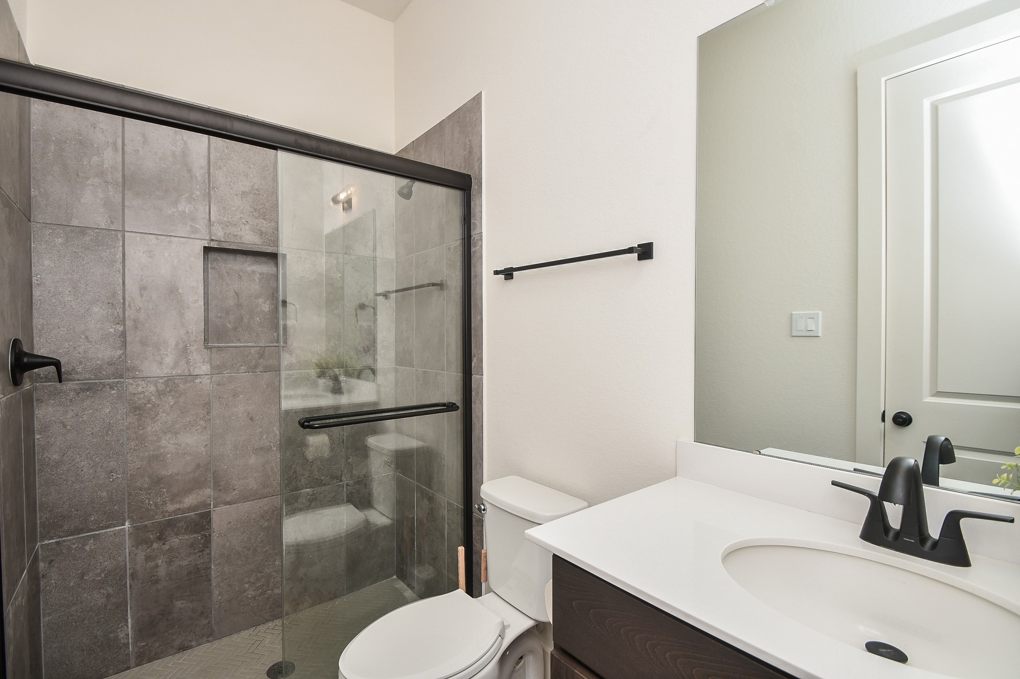31915 Sky Rdg Lane Fulshear, TX 77441 - Photo 36 of 38 Discover elegance in secondary bathroom, featuring sleek gray tiles, a modern glass shower, and chic black fixtures for a contemporary touch.