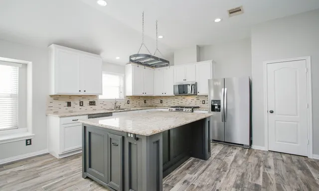 a kitchen with a sink a stove a refrigerator and white cabinets