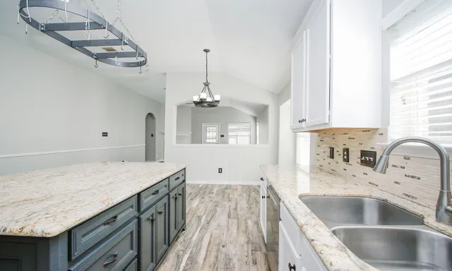 a kitchen with kitchen island granite countertop a sink a counter space appliances and cabinets