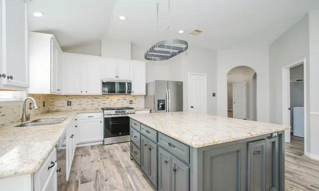 a kitchen with a sink dishwasher a stove top oven a refrigerator with island and cabinets