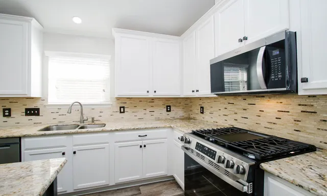 a kitchen with granite countertop a stove sink and cabinets