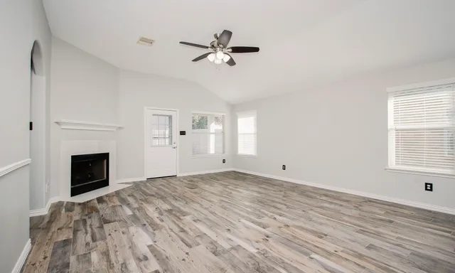 a view of empty room with wooden floor and fireplace
