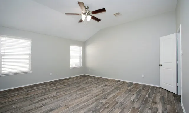 a view of empty room with wooden floor and fan