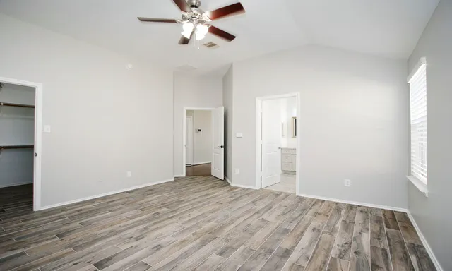 a view of empty room with wooden floor and fan