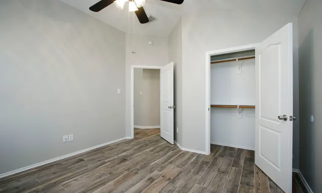 an empty room with closet and a ceiling fan