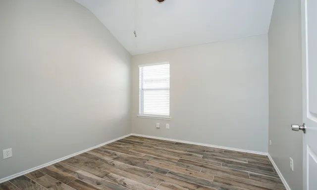 a view of empty room with wooden floor