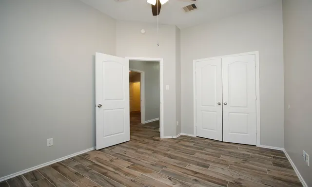 a view of an empty room with window and wooden floor