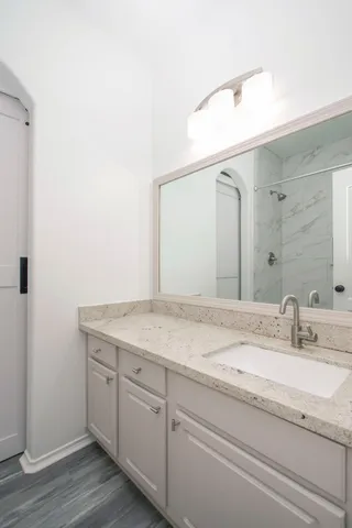 a bathroom with a granite countertop sink and white cabinets