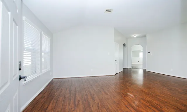 a view of empty room with wooden floor and window