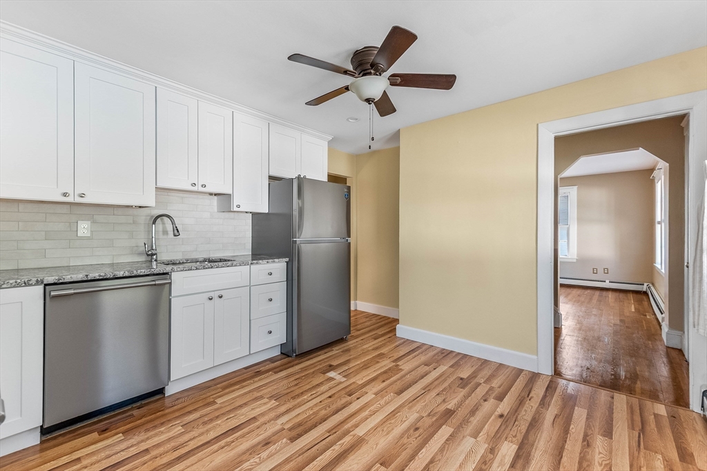 1 Columbia Terrace Dedham, MA 02026 - Photo 4 of 24 a kitchen with granite countertop a refrigerator a sink and white cabinets