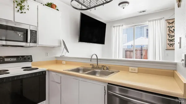 a kitchen with stainless steel appliances a sink dishwasher stove and microwave with wooden floor