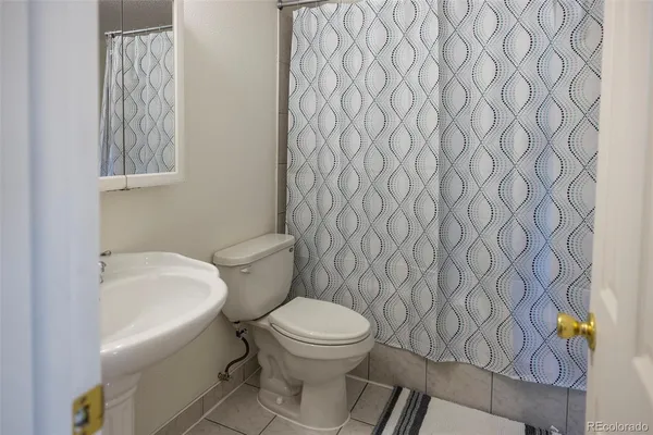 a white toilet sitting next to a white sink and a shower curtain