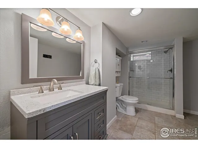 a bathroom with a granite countertop sink toilet a mirror and shower