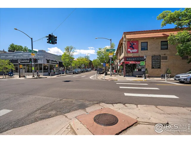 a view of road with card parked on side and retail shops