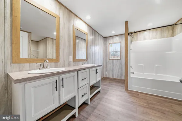 a spacious bathroom with a double vanity sink a mirror and a bathtub