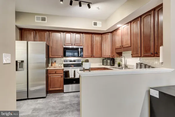 a kitchen with stainless steel appliances granite countertop a refrigerator stove top oven and sink