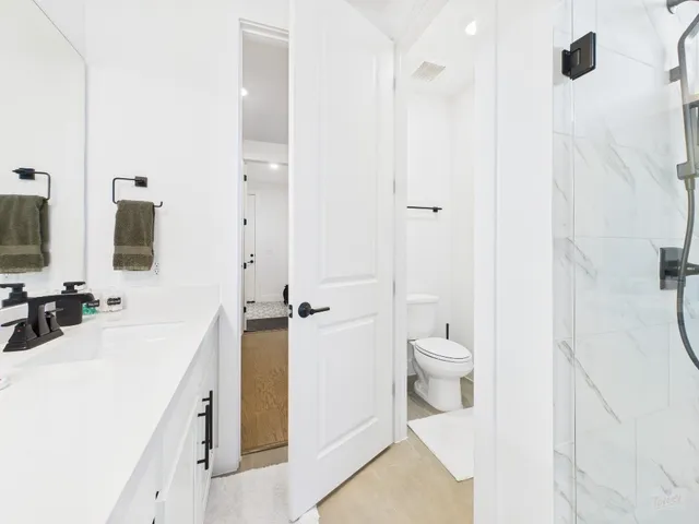 a spacious bathroom with a double vanity sink a toilet and a shower