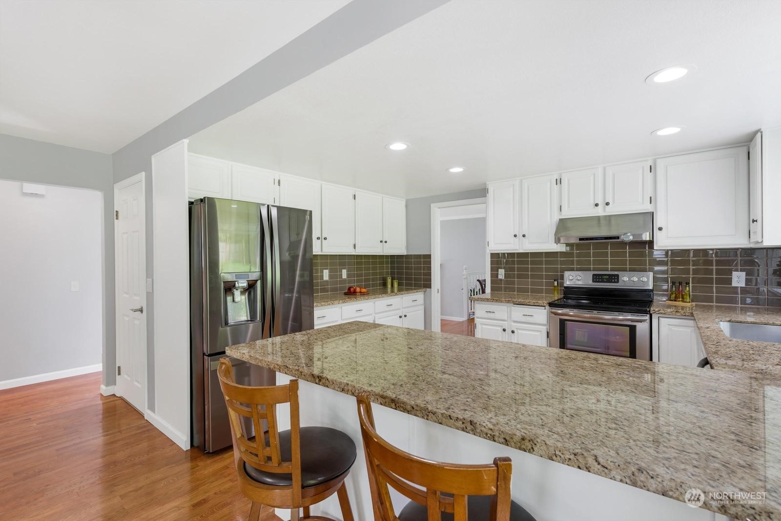 17218 3rd Avenue Southeast Bothell, WA 98012 - Photo 9 of 28 a kitchen with stainless steel appliances granite countertop a stove a sink a refrigerator a microwave and white cabinets with wooden floor