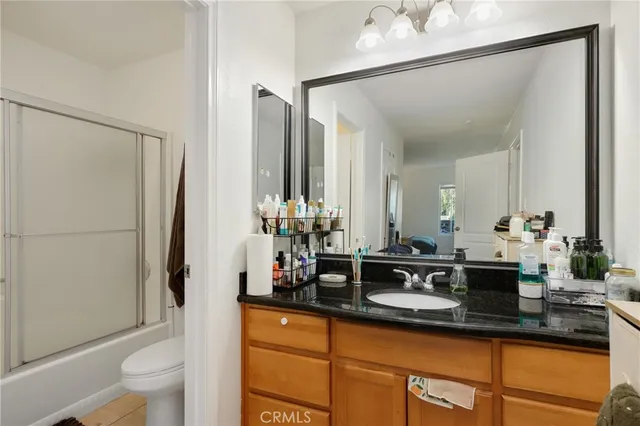a bathroom with a granite countertop sink a toilet a mirror and shower
