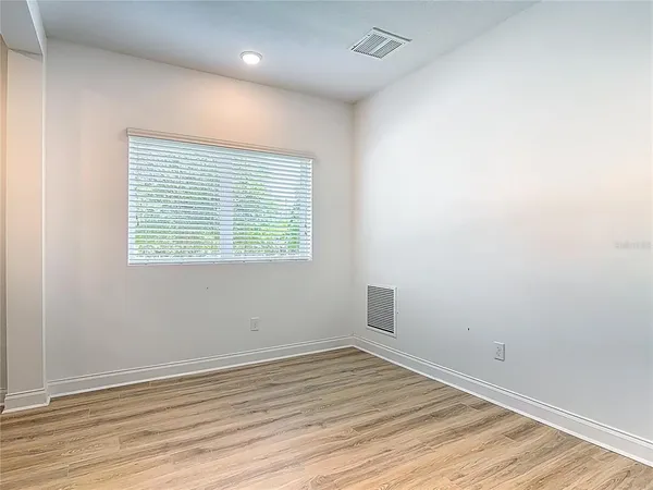 a view of an empty room with a window and wooden floor