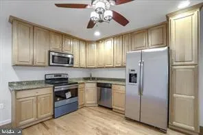 a kitchen with stainless steel appliances granite countertop a refrigerator a stove a sink and dishwasher a oven with white cabinets