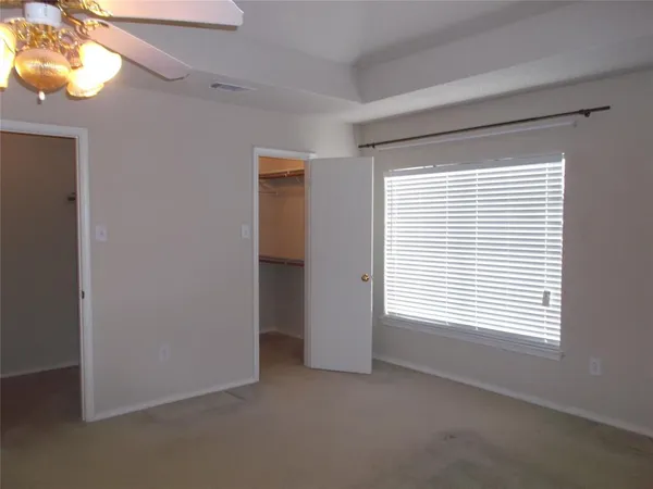 an empty room with a ceiling fan and window