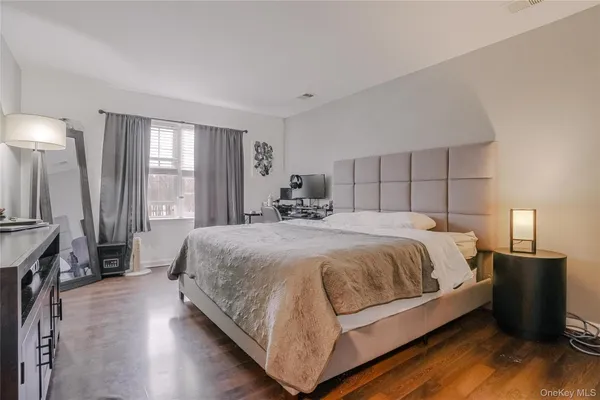 a spacious bedroom with a bed and wooden floor